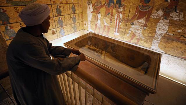 A guard looks at ancient Egyptian drawings and the sarcophagus in the newly renovated tomb wall of boy pharaoh King Tutankhamun in the Valley of the Kings in Luxor