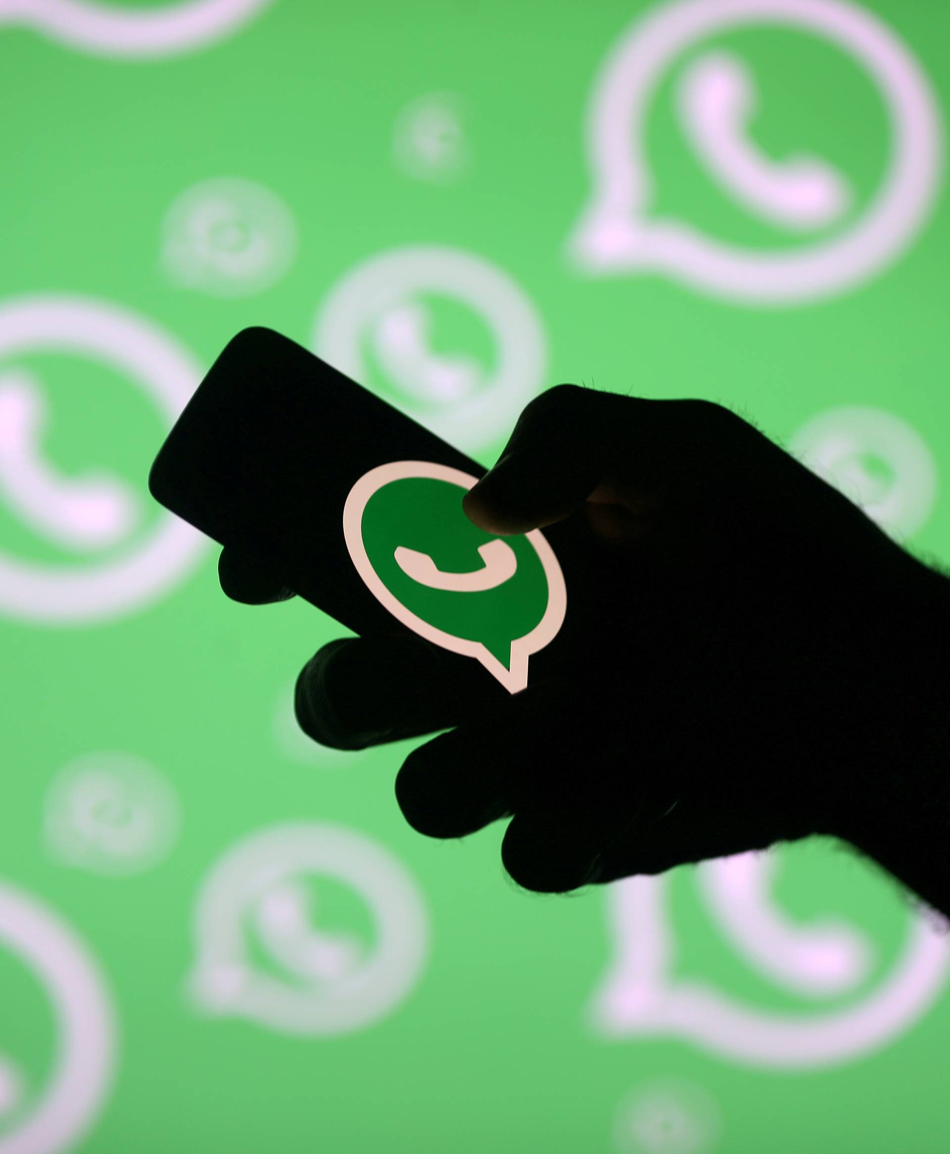 FILE PHOTO: A man poses with a smartphone in front of displayed Whatsapp logo in this illustration
