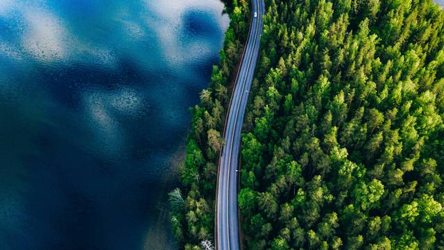 Aerial,View,Of,Road,Between,Green,Summer,Forest,And,Blue