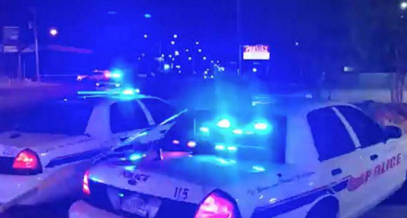 Police vehicles are seen near the scene in the aftermath of a drive-by shooting at a liquor store in Shreveport, Louisiana