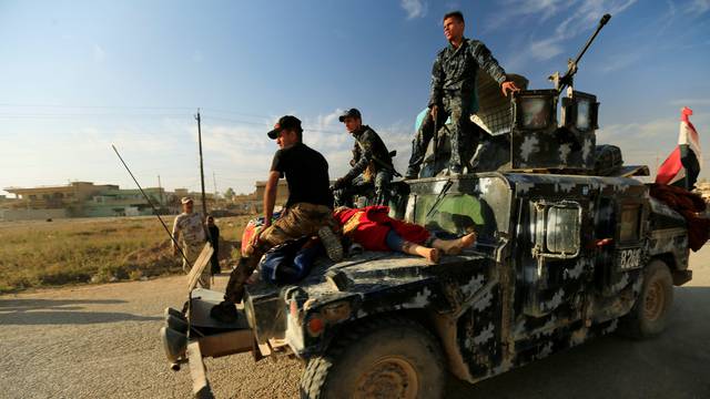 Members of Iraqi security forces help displaced people who fled Hammam al-Alil, south of Mosul, to head to safer territory