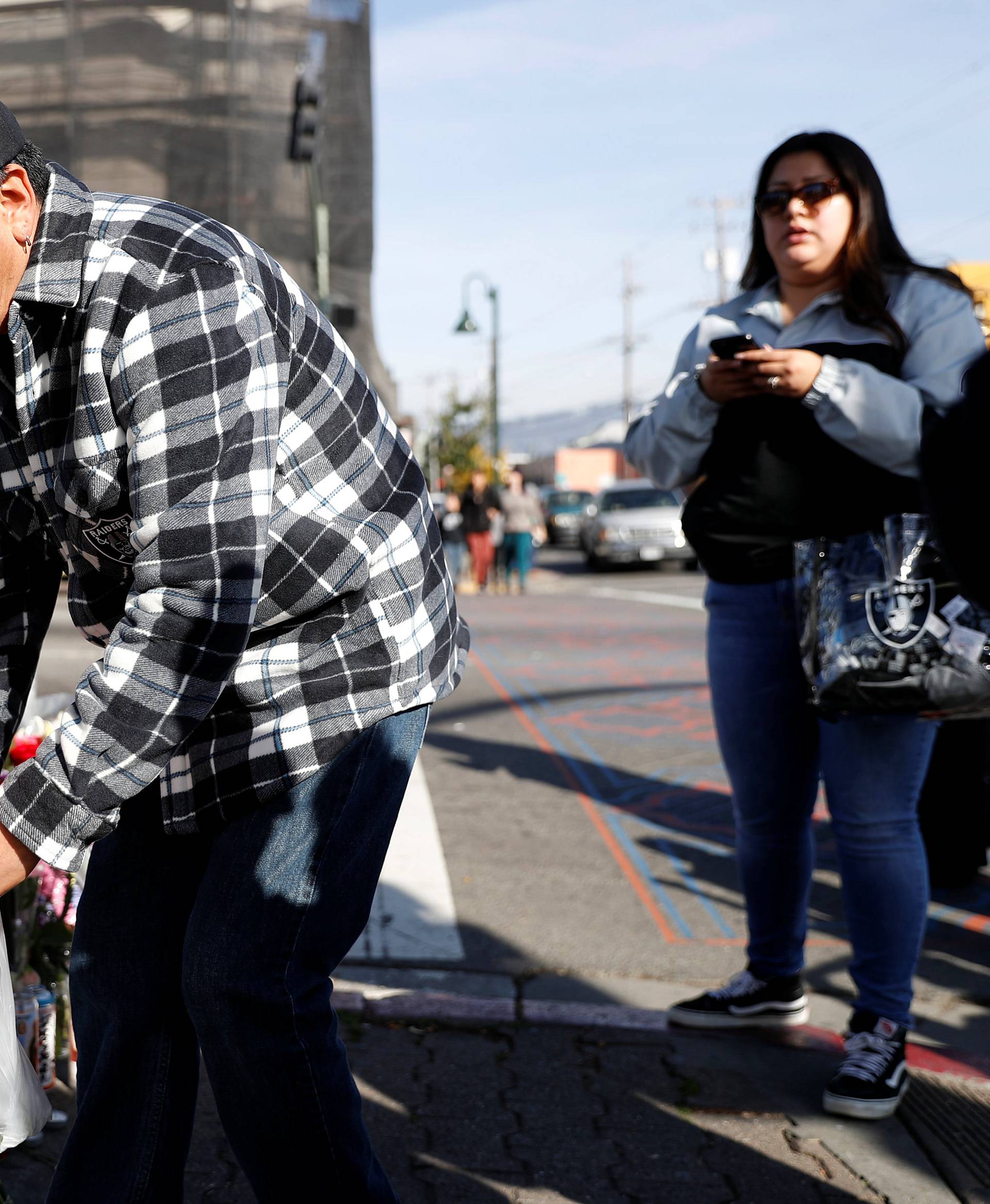 Joel Cruz, of Milpitas, places flowers at a makeshift memorial near the scene of a fire in the Fruitvale district of Oakland, California