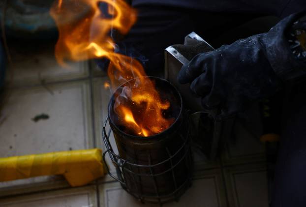 Bee rescuer Clarence Chua prepares a bee smoker to calm a honey bee nest found in the balcony of a public housing apartment in Singapore