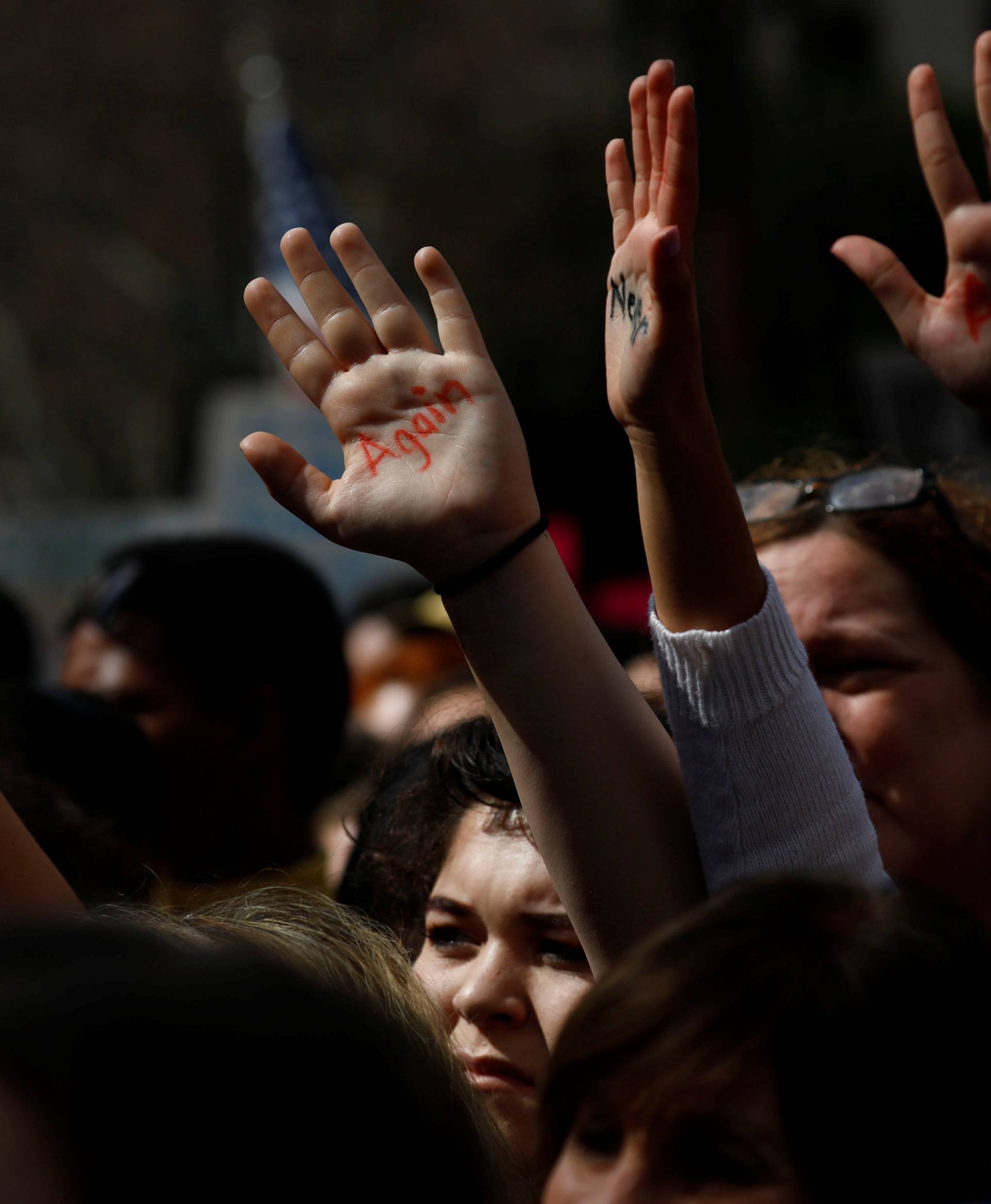 People hold their hands into the air painted with "never again" during "March for Our Lives", an organized demonstration to end gun violence, in downtown Los Angeles