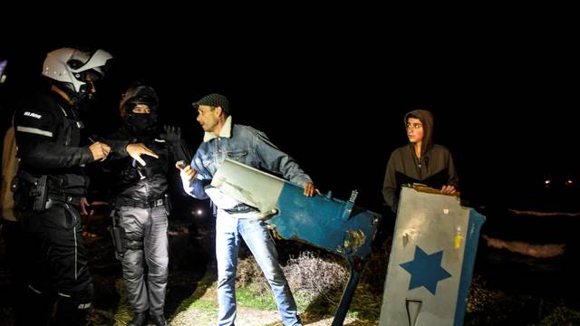Policemen speak with Israelis as they hold parts of a military helicopter at the shore after it crashed off the coast of the Mediterranean near Haifa as local media said