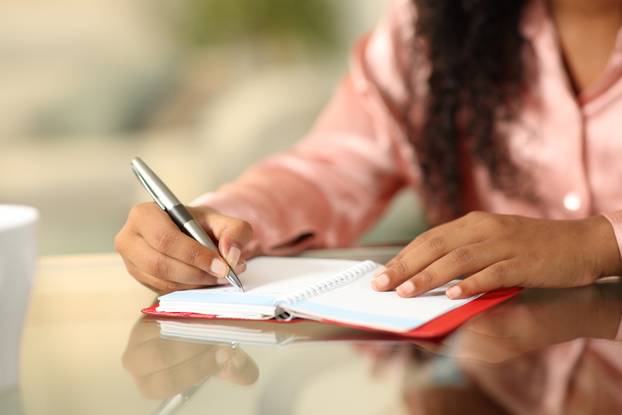 Black woman hands writing in agenda