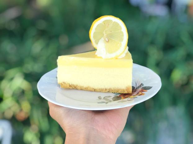 Asian woman hold luxury plate of lemoncheesecake in her hand ove