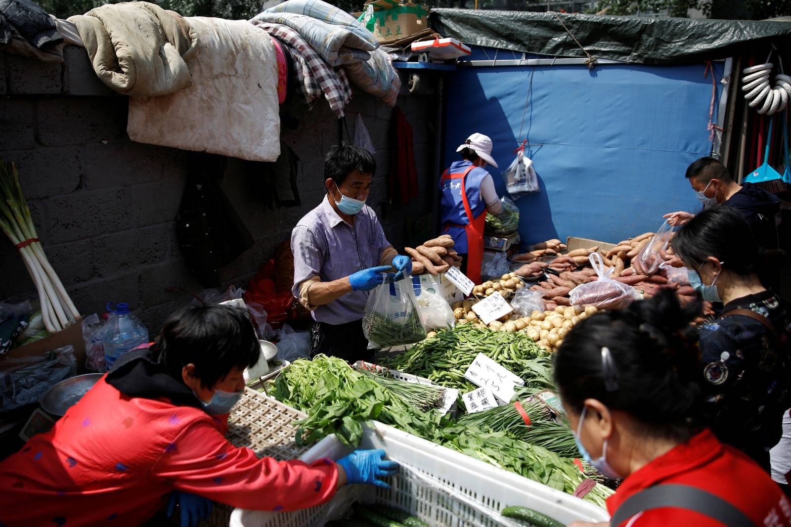 A vegetable stall vendor wearing a face mask attends to customers at an outdoor market in Beijing, following the novel coronavirus disease (COVID-19) outbreak