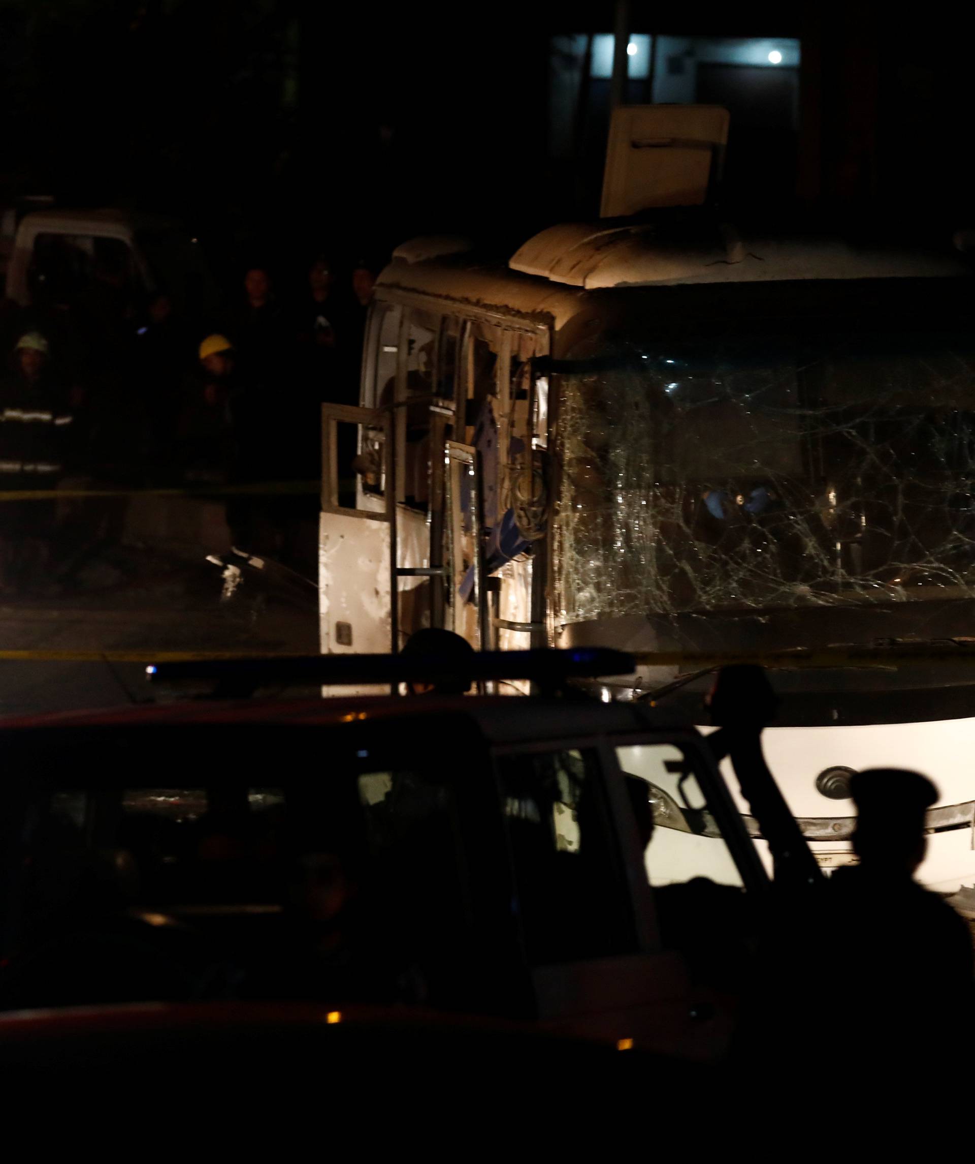 Police officers inspect a scene of a bus blast in Giza