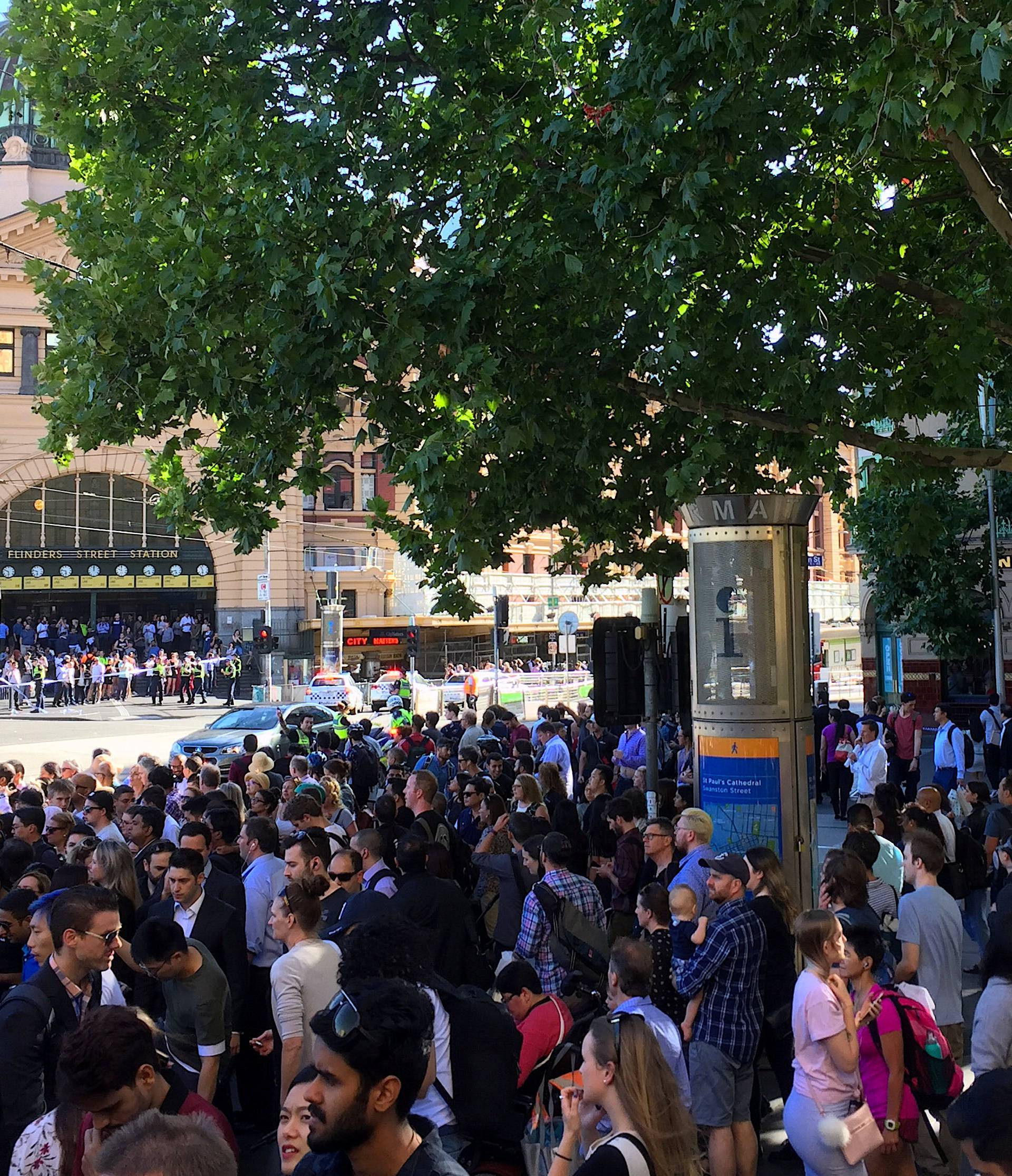 Members of the public stand behind police tape after Australian police said on Thursday they have arrested the driver of a vehicle that ploughed into pedestrians at a crowded intersection near the Flinders Street train station in central Melbourne