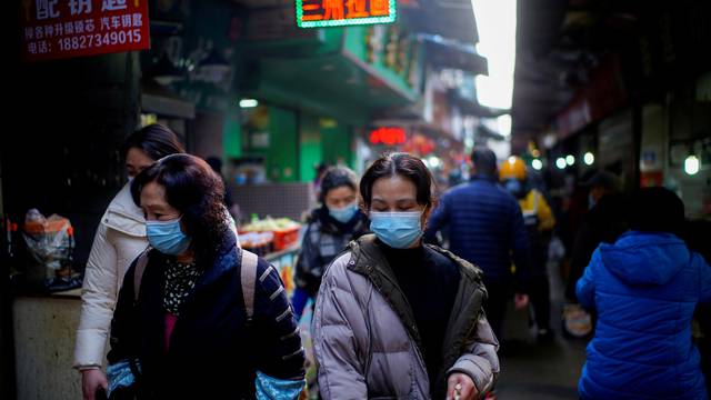 FILE PHOTO: People wearing face masks walk on a street market in Wuhan