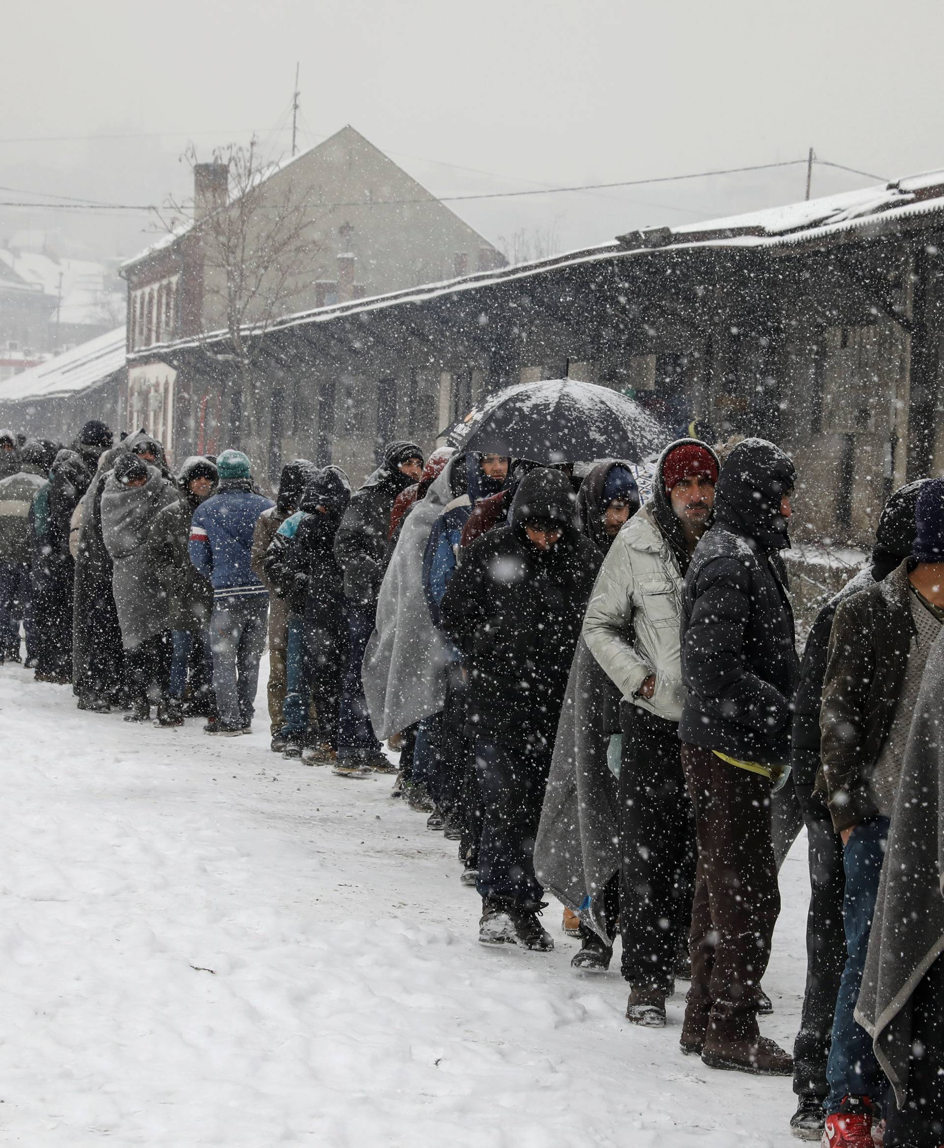 Migrants stand in line to receive free food outside a derelict customs warehouse in Belgrade