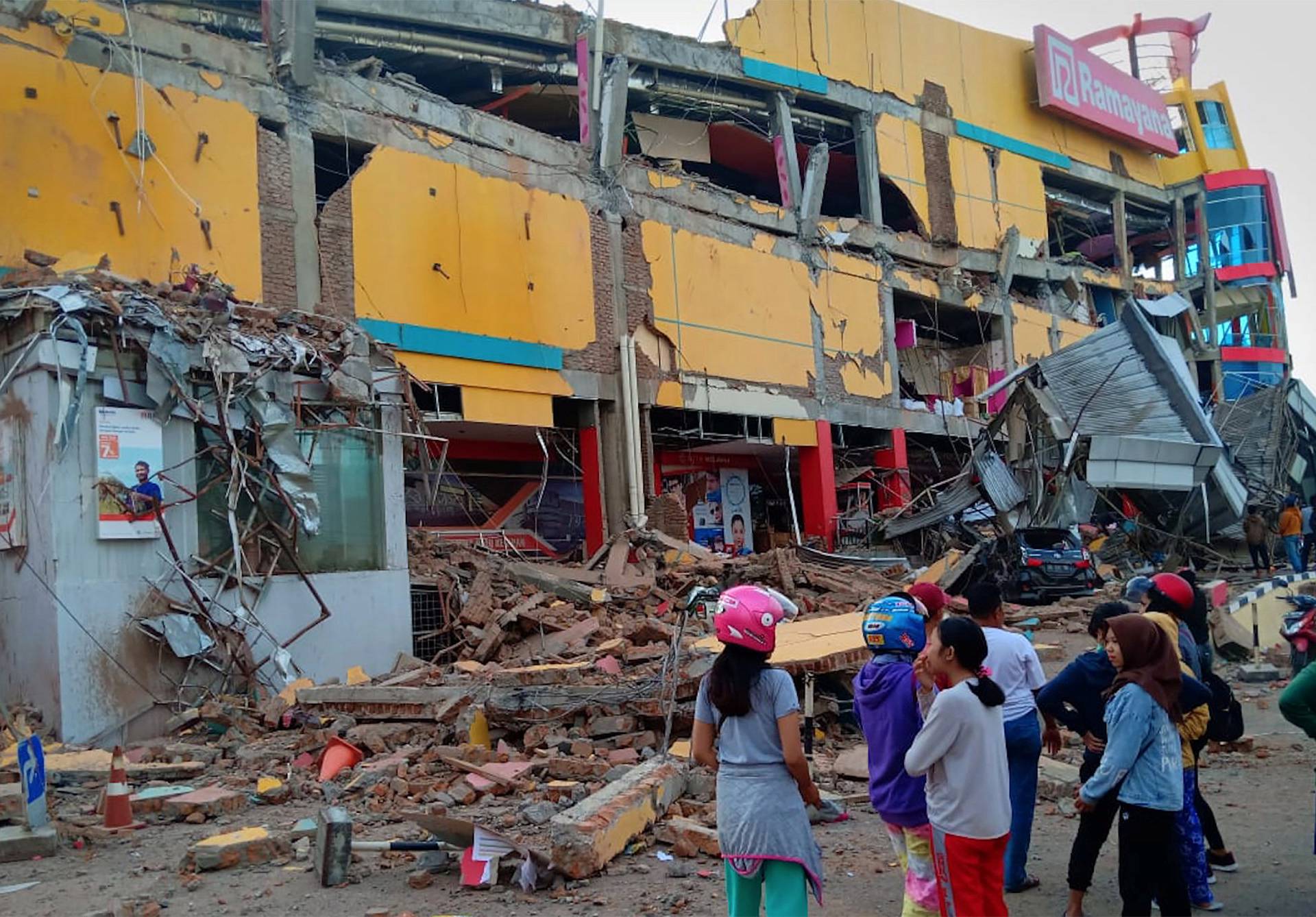 Residents stand in front of a damaged shopping mall after an earthquake hit Palu