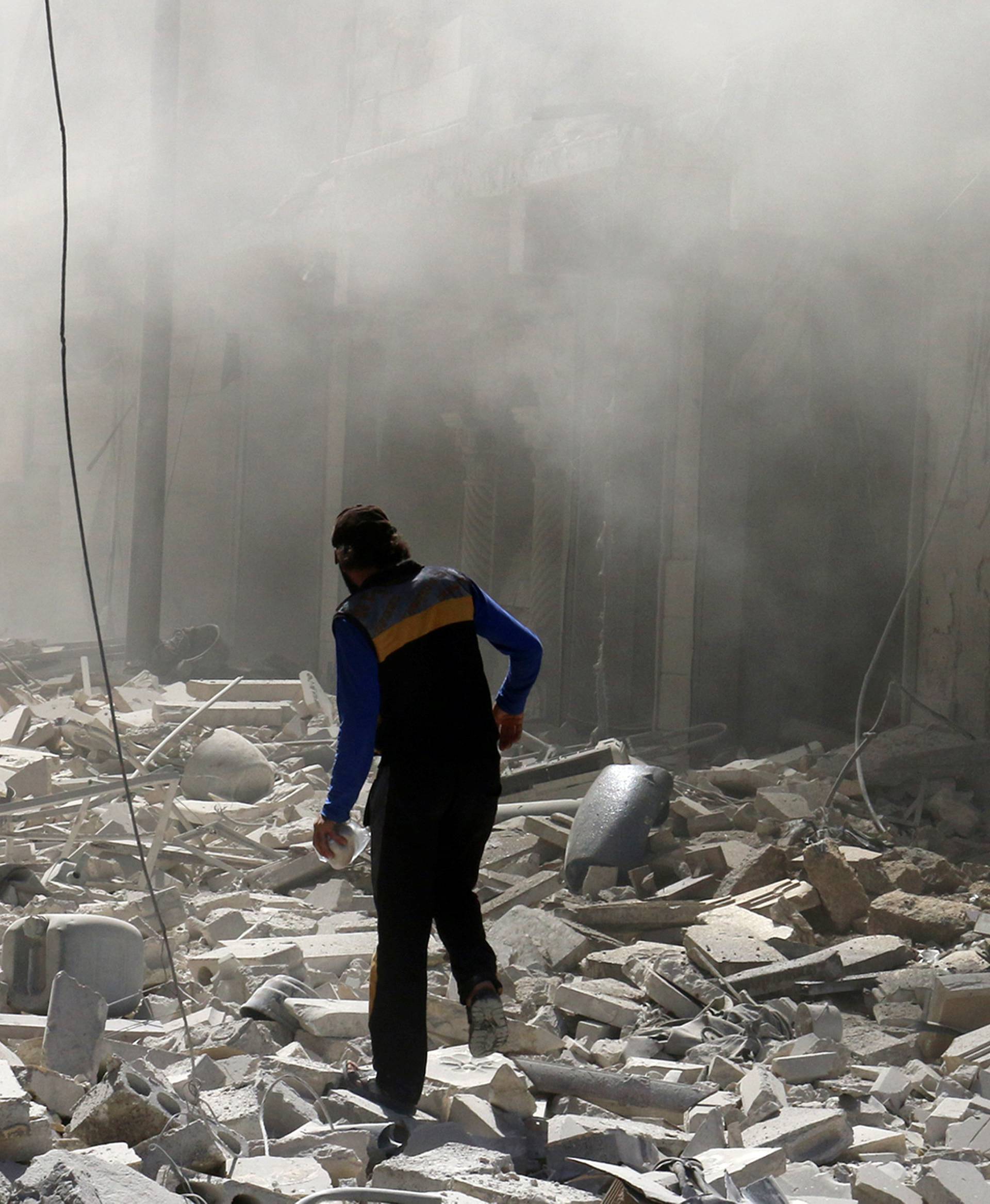 A man walks on the rubble of damaged buildings after an airstrike on the rebel held al-Qaterji neighbourhood of Aleppo