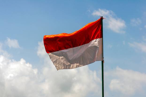 An Indonesia Flag on old paper with blue sky background