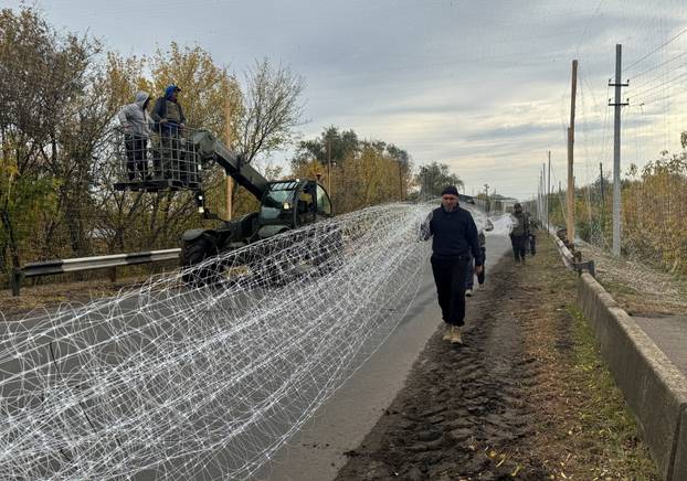 Ukrainian servicemen install anti-drone nets over a road near the frontline town of Dobropillia