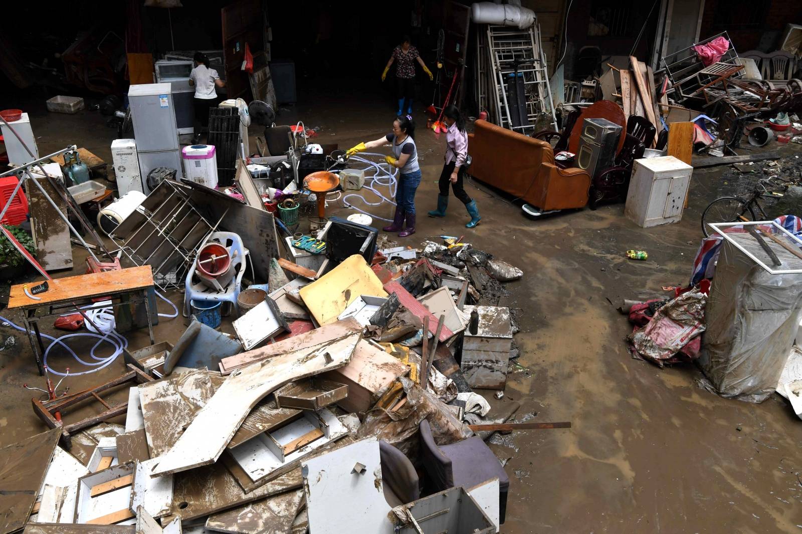 Residents clean up their belongings after their houses were hit by flood following heavy rainfall in Sanming