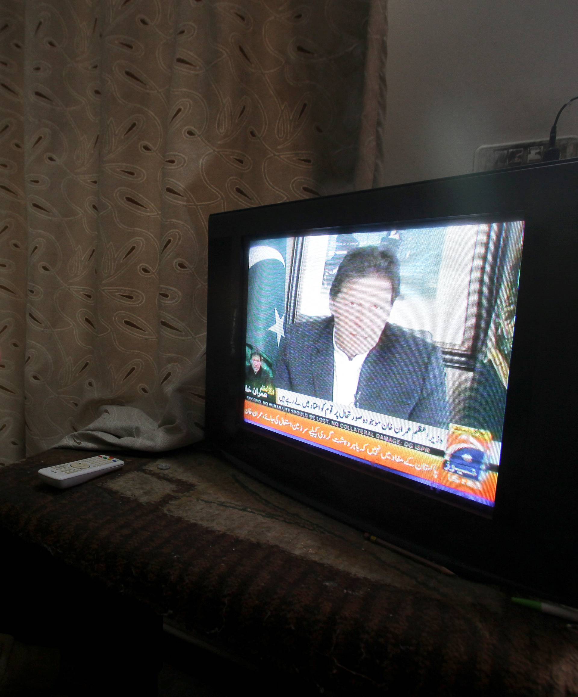 A man watches the speech of the Pakistani Prime Minister Imran Khan, after Pakistan shot down two Indian planes, in Lahore