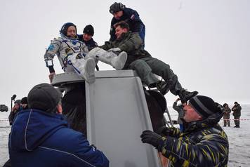 Ground personnel help Alexander Misurkin of Russia to get out of the Soyuz MS-06 space capsule after landing in a remote area outside the town of Dzhezkazgan