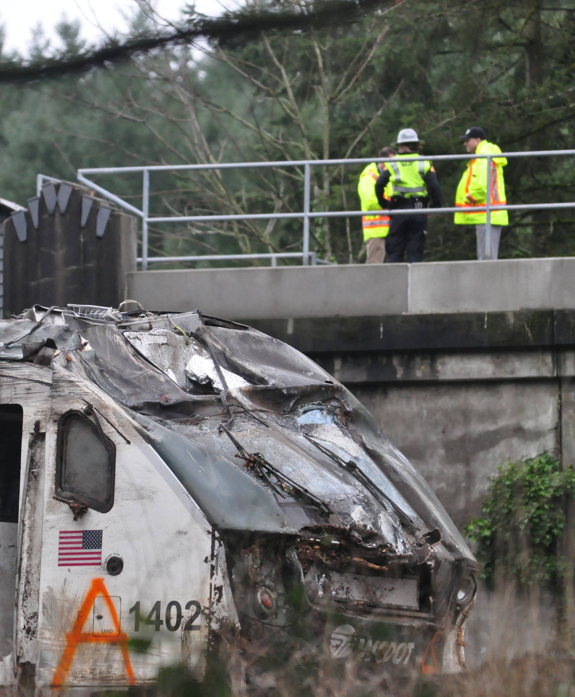 First responders are seen at the scene of an Amtrak passenger train which derailed and is hanging from a bridge over the I-5 in DuPont