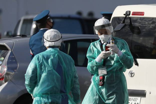 Health officials dressed in protective gear are seen near the cruise ship Diamond Princess at Daikoku Pier Cruise Terminal in Yokohama