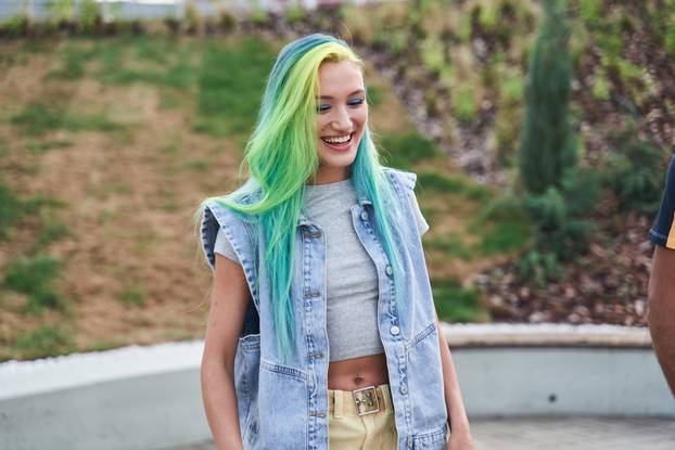 Young girl with color hair laughing out loud while walking at the street