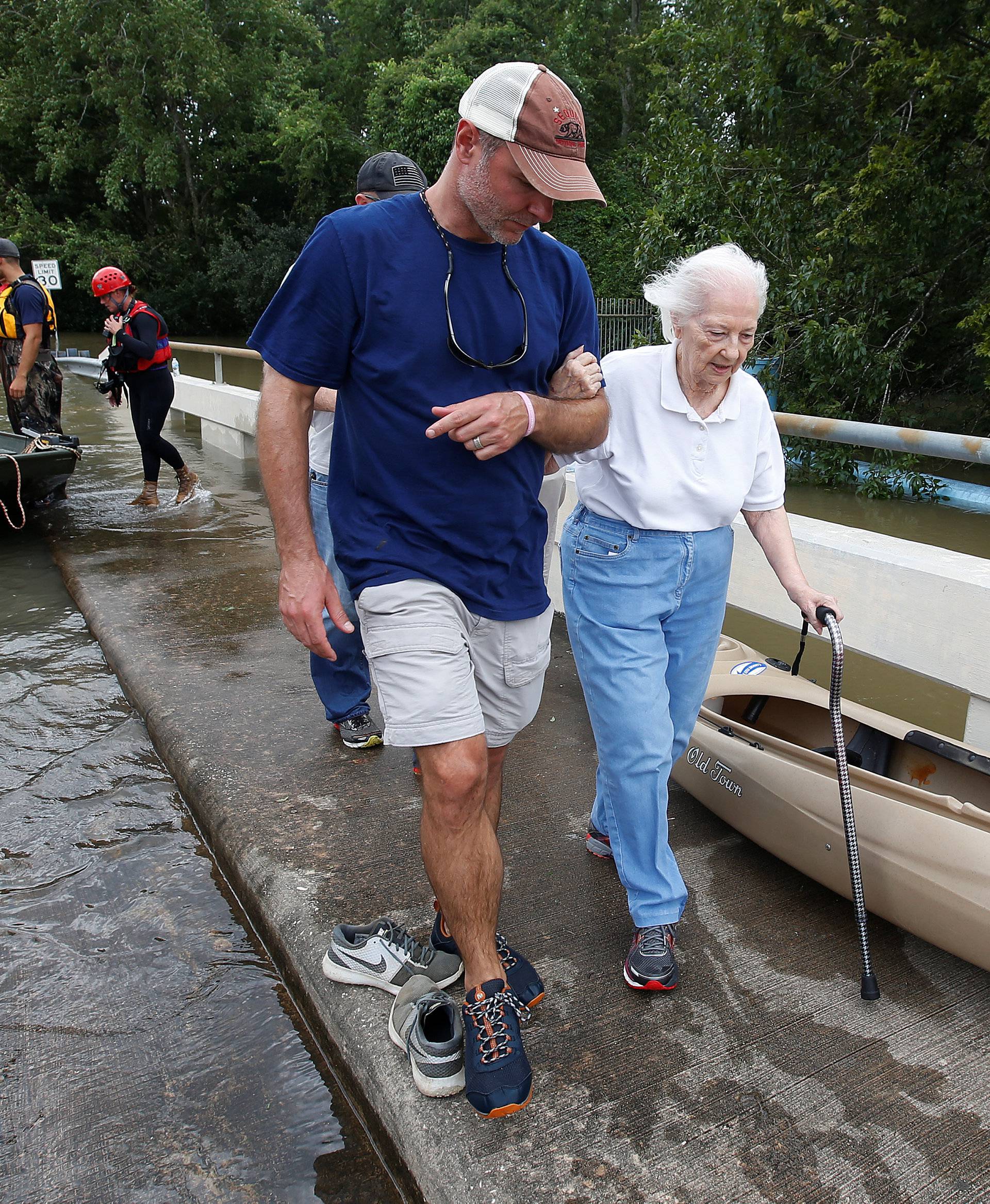 People walk across a bridge to evacuate from the rising waters of Buffalo Bayou following Hurricane Harvey in a neighborhood west of Houston