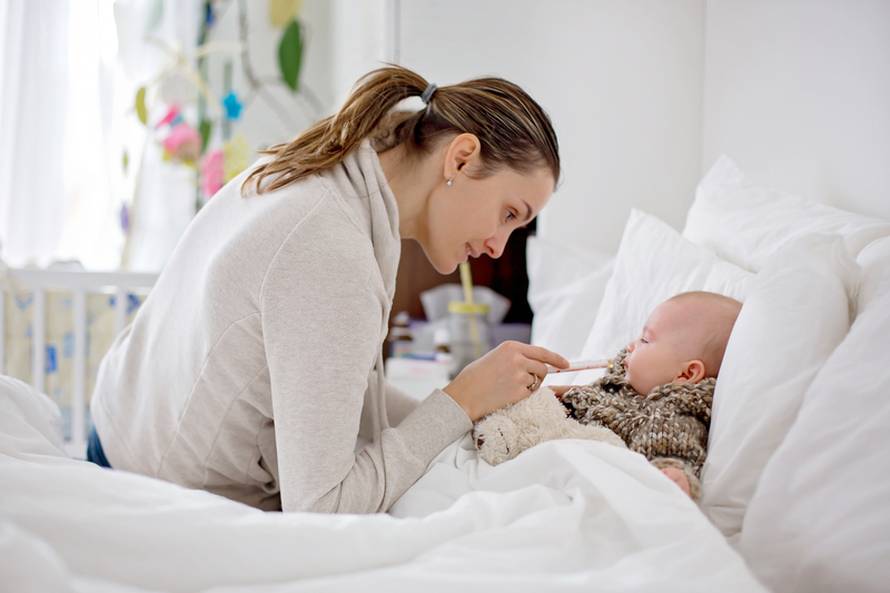 Cute sick child, baby boy, staying in bed, mom giving him medici