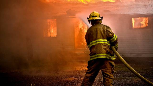 Firefighter spraying water at a house fire