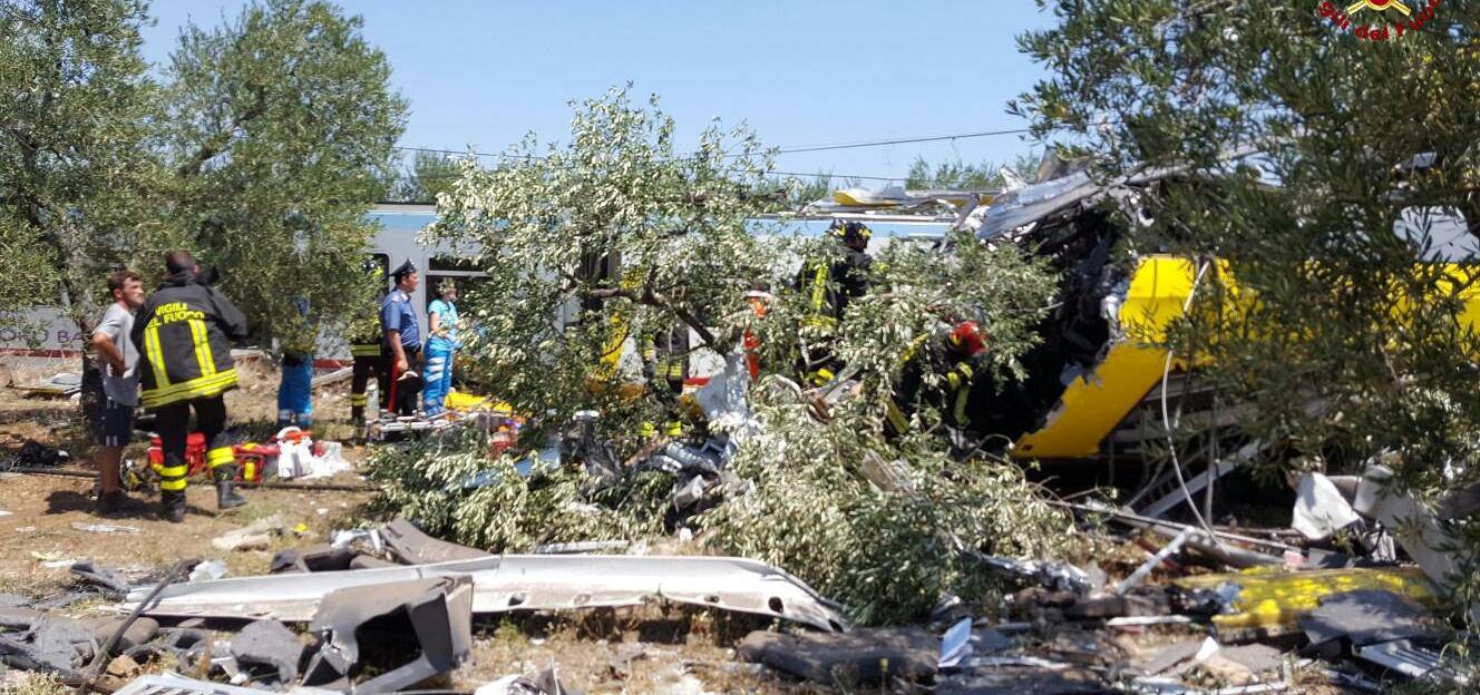 Firefighters work at the site where two passenger trains collided in the middle of an olive grove in the southern village of Corato