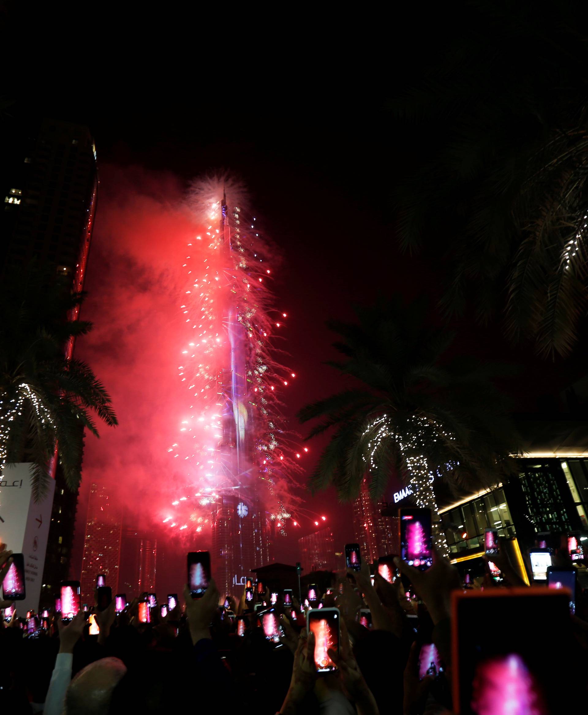 People watch as the Burj Khalifa is lit up during the New Year celebrations in Dubai