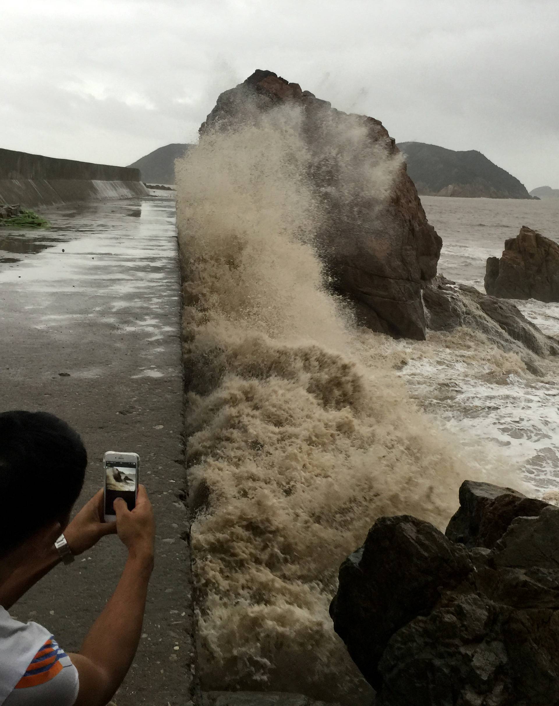 A man records waves whipping the shore before Typhoon Meranti makes a landfall on southeastern China, in Wenling