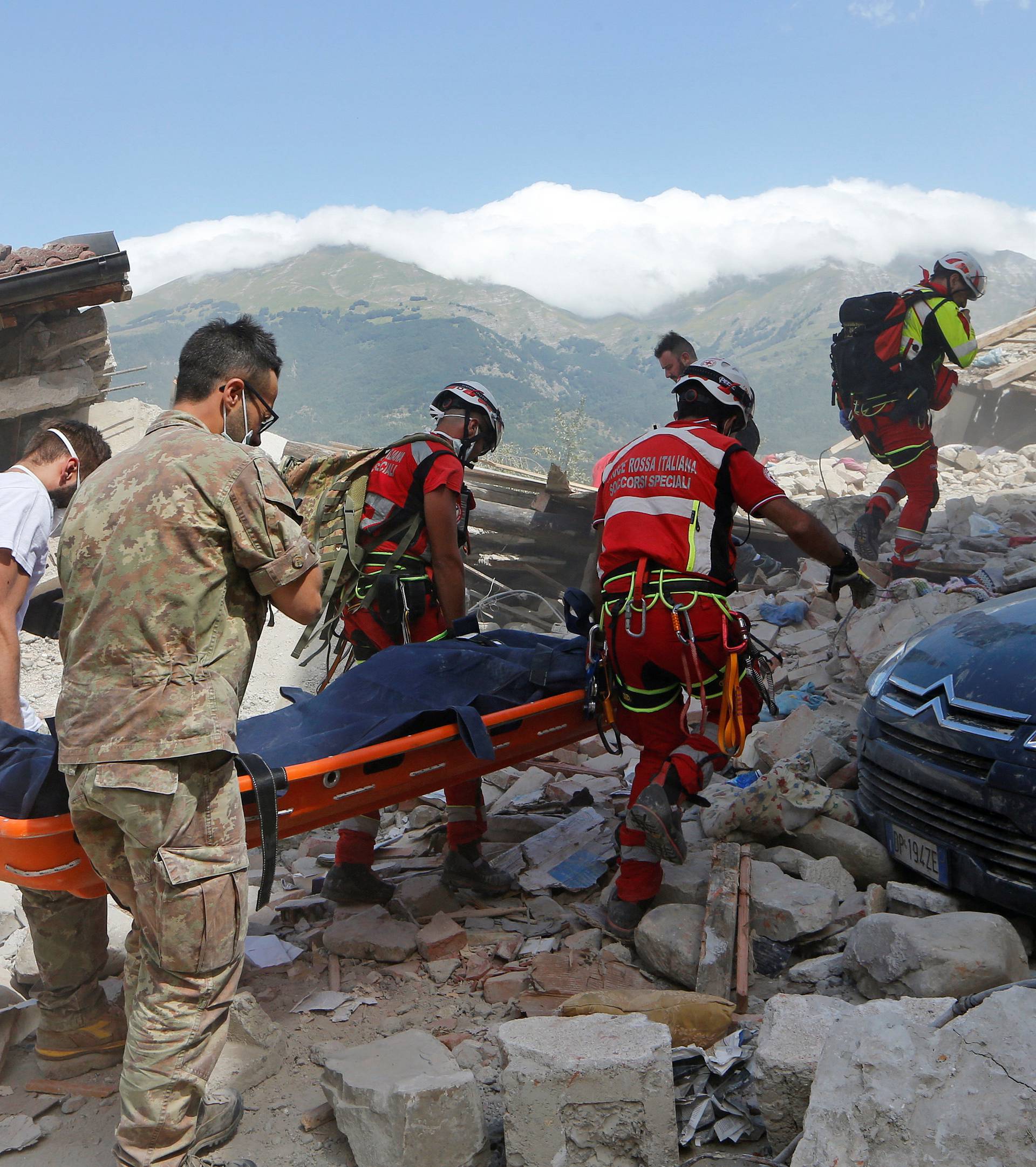 A body is carried away by rescuers following an earthquake in Amatrice