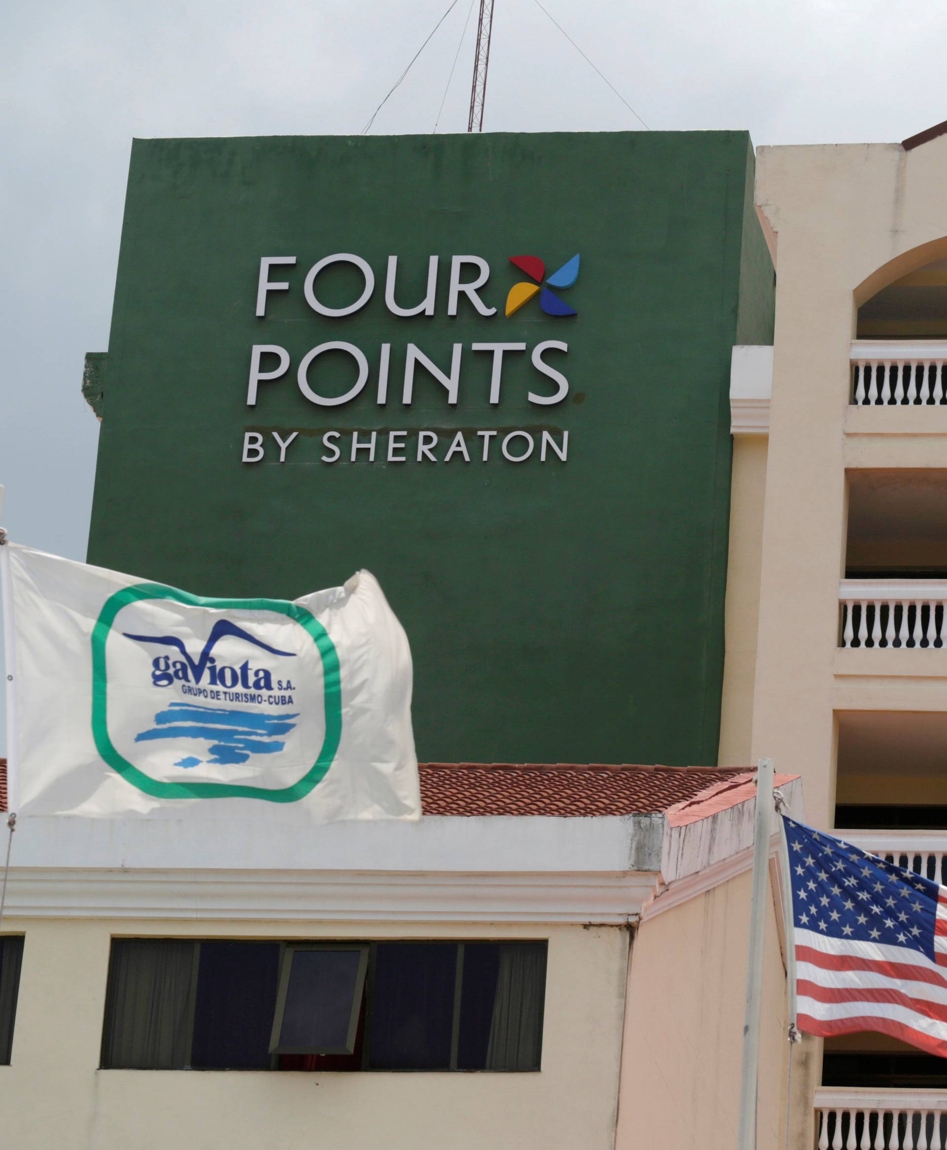 A U.S. flag and a flag of the Cuban military-run hospitality company Gaviota flutter near the logo of a  "Four Points by Sheraton" hotel in Havana