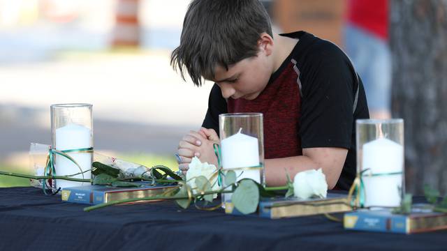 A young boy prays during a vigil held at the Texas First Bank after a shooting left several people dead at Santa Fe High School in Santa Fe, Texas