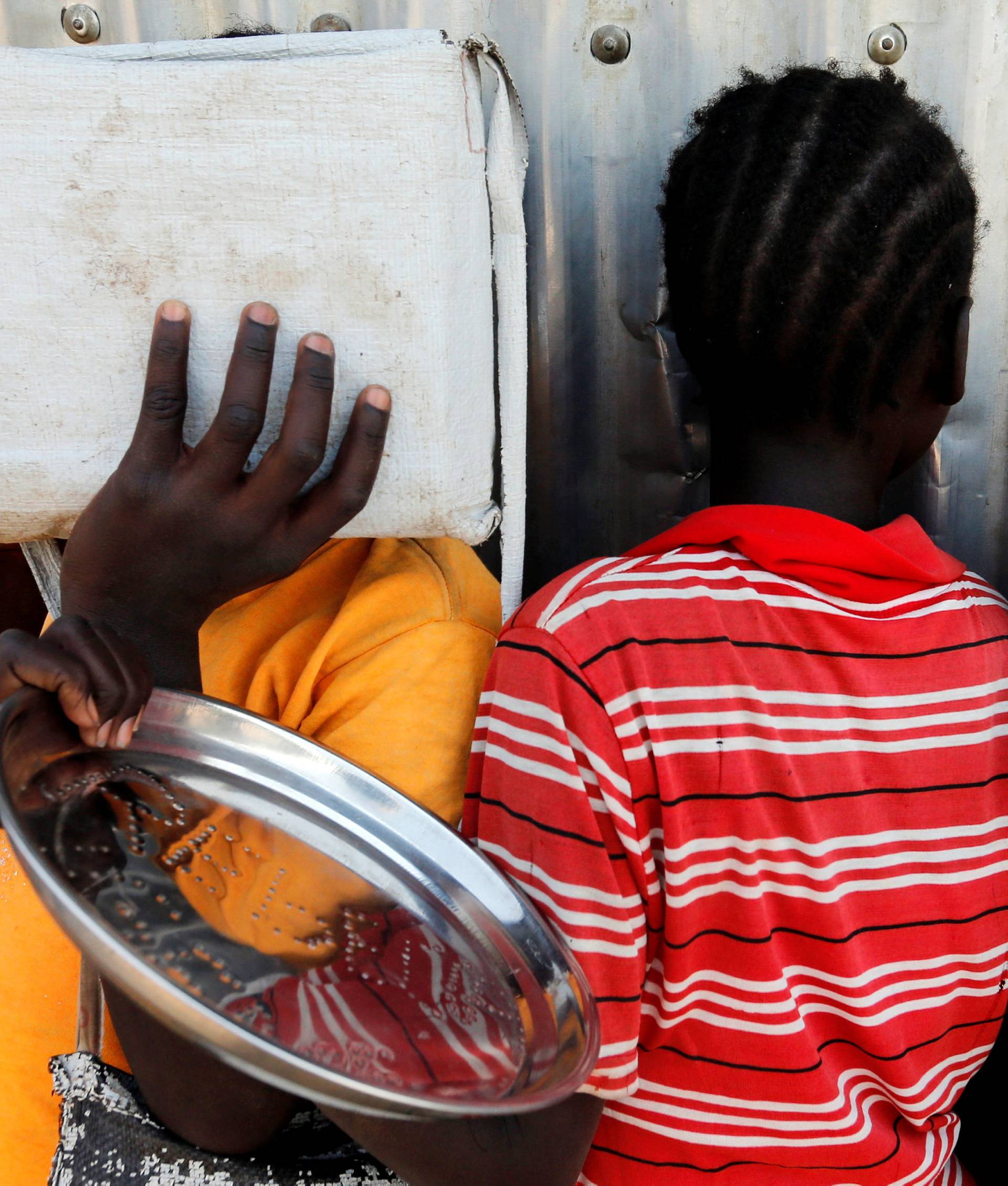 South Sudanese refugees children hide their faces as they queue to receive food at the Kalobeyei Primary school within Kalobeyei Settlement outside the Kakuma refugee camp in Turkana county