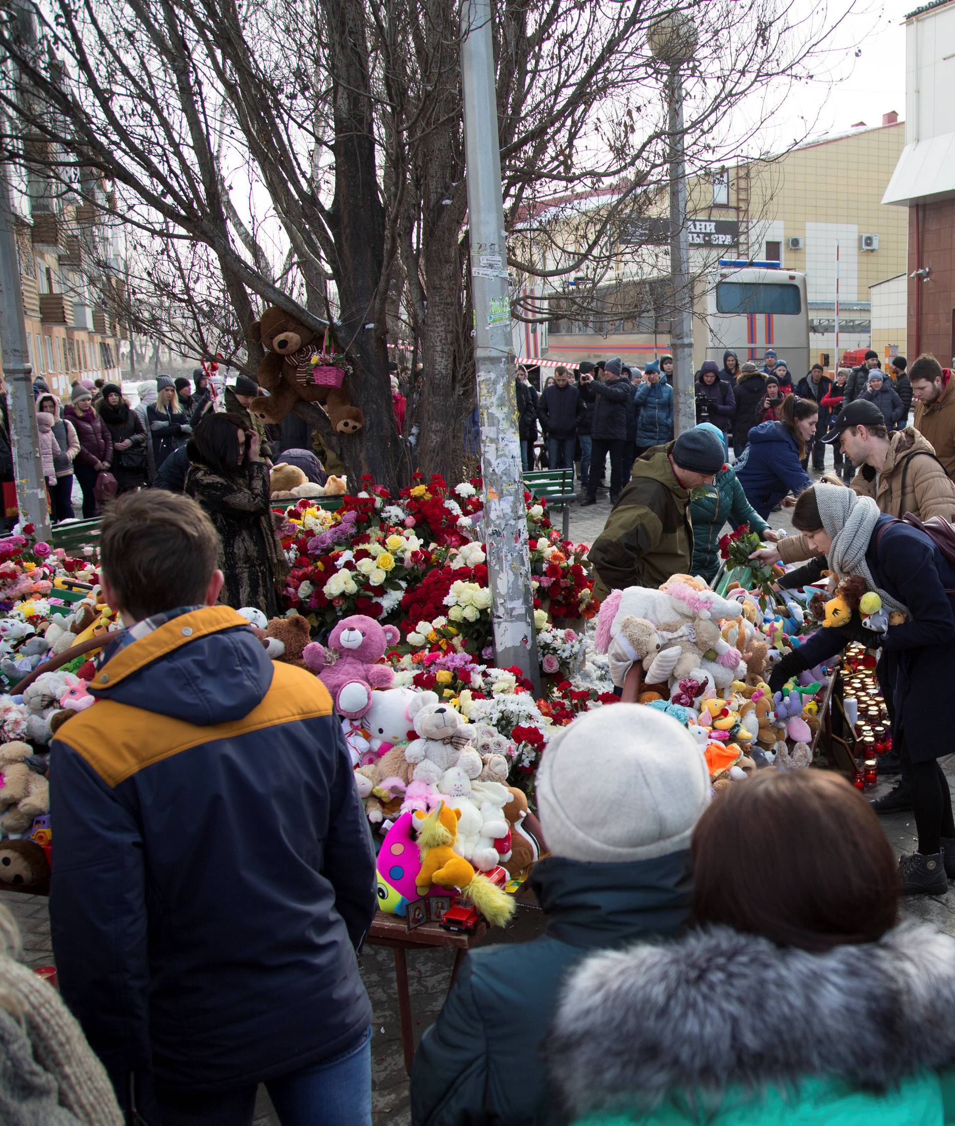 People gather at a makeshift memorial for the victims of a shopping mall fire in the Siberian city of Kemerovo