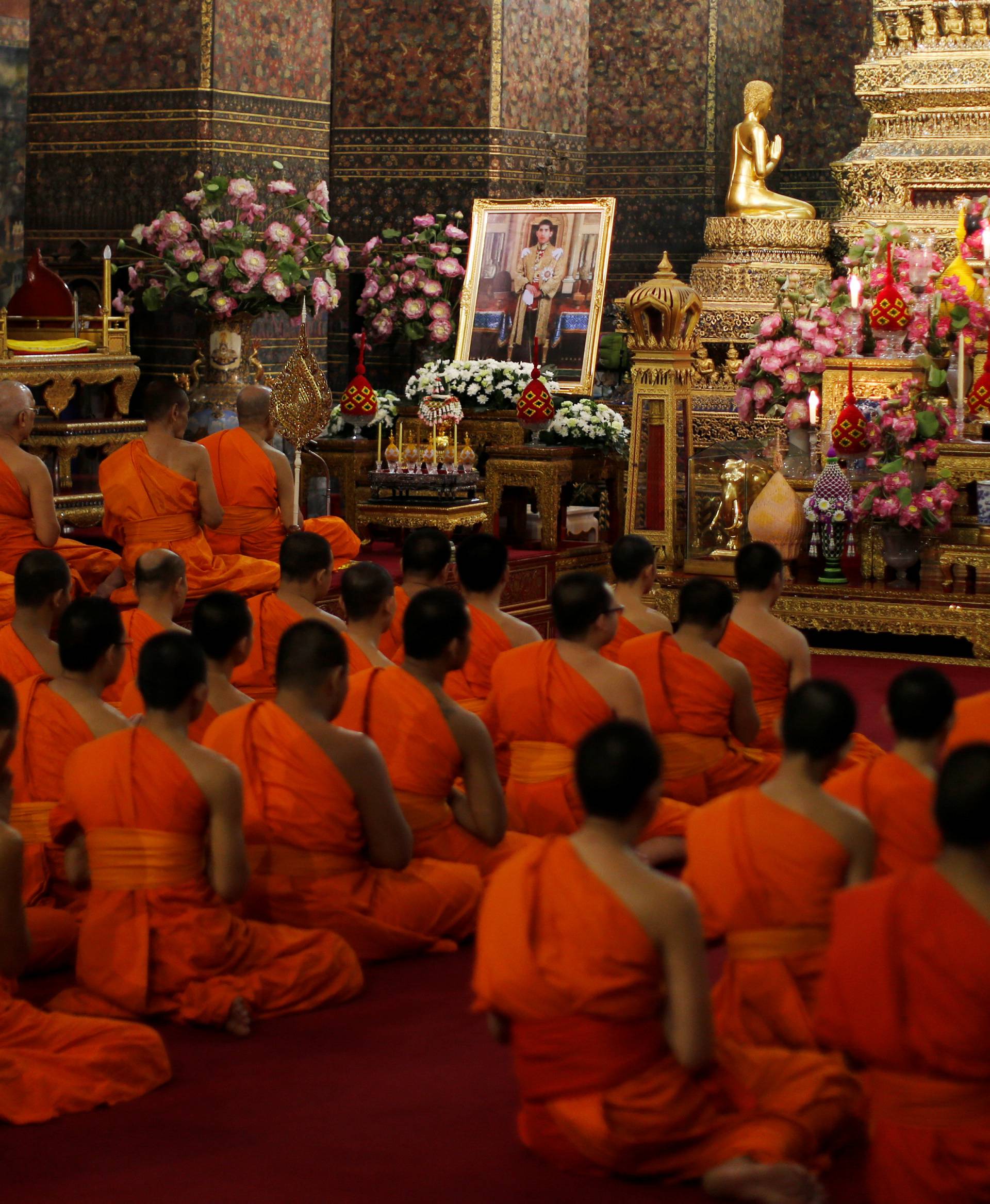 Buddhist monks pray in front of a picture of Thailand's new King Maha Vajiralongkorn Bodindradebayavarangkun at Wat Pho temple in Bangkok