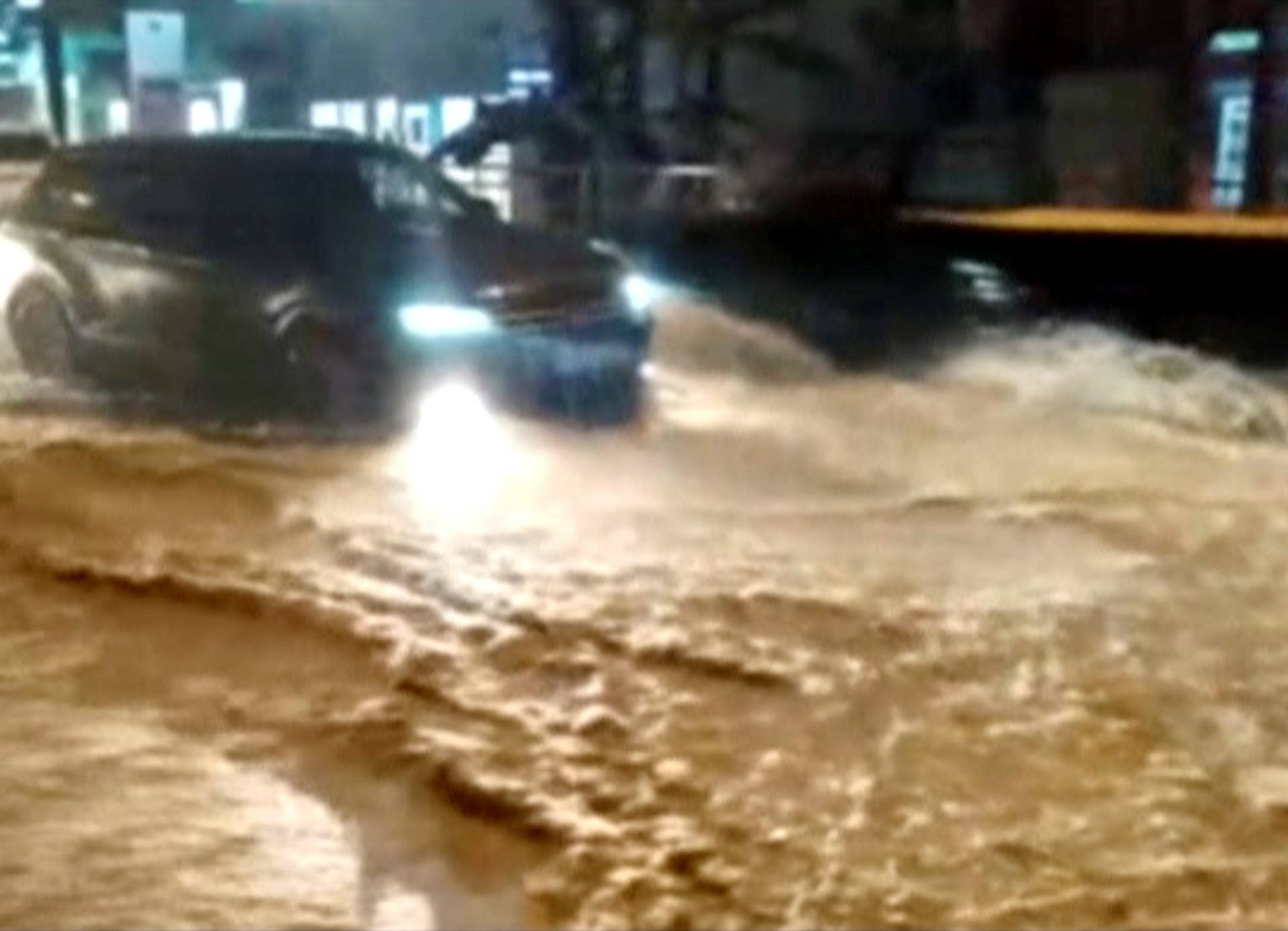 A still image shows vehicles driving along a street in a settlement affected by floodwaters in Krasnodar Region