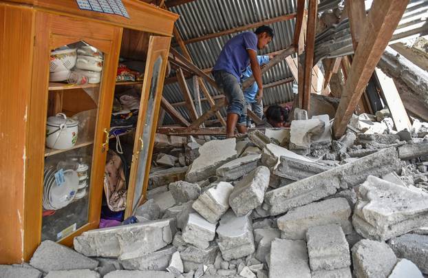 A villager walks through the ruins of a collapsed house during a search for the equipment of Malaysian tourists who died during the earthquake at the Sembalun Selong village in Lombok Timur