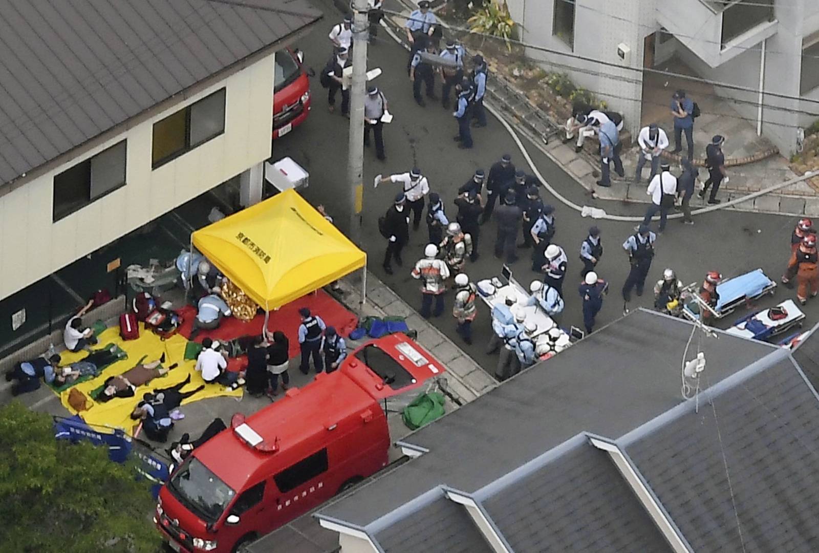 Rescue workers carry injured people from the three-story Kyoto Animation building which was torched in Kyoto