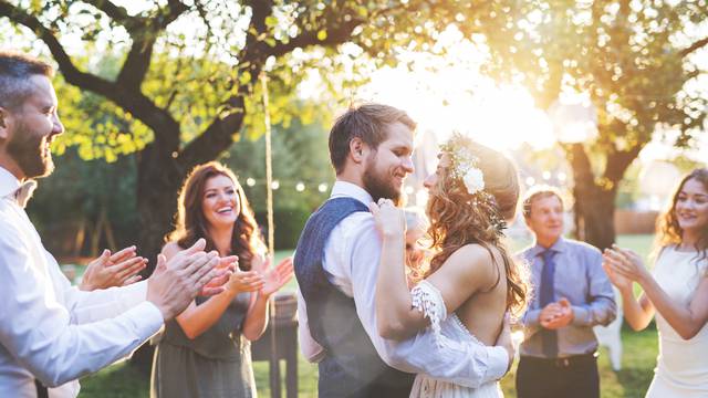 Bride and groom dancing at wedding reception outside in the backyard.