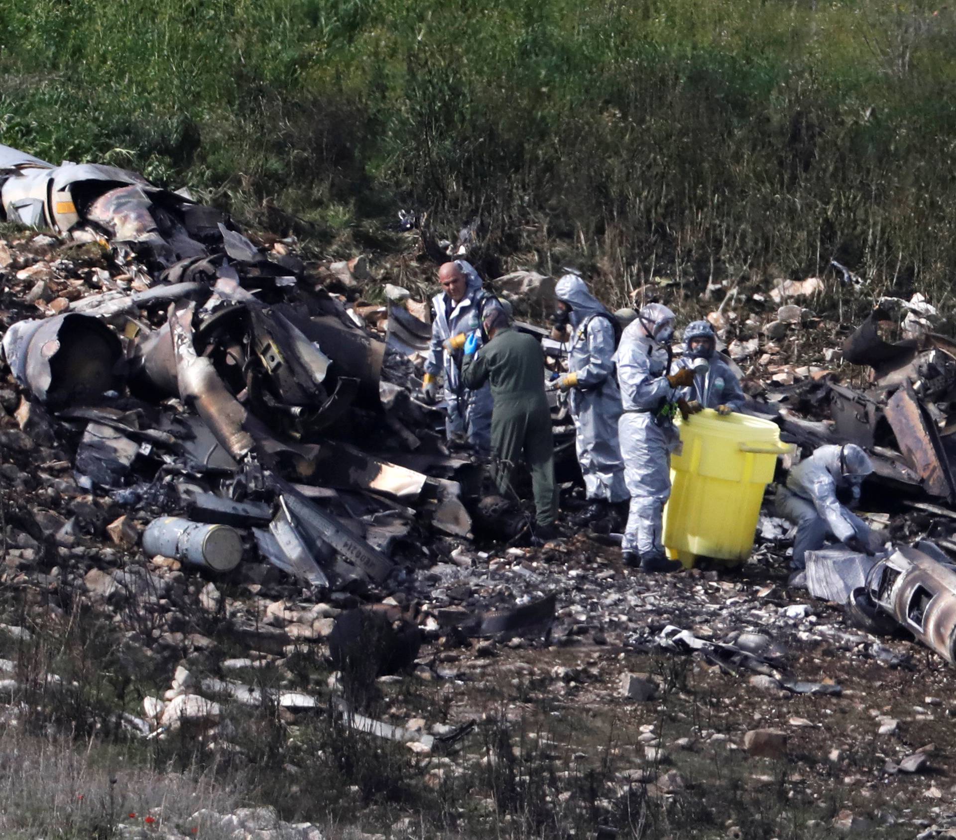 Israeli security forces examine the remains of an F-16 Israeli war plane near the village of Harduf