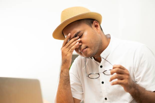 Young asian casual business man take off glasses and rubbing his