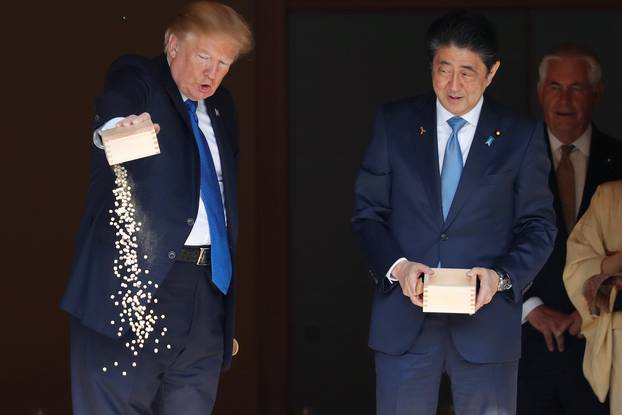 U.S. President Donald Trump pours fish food out as Japan