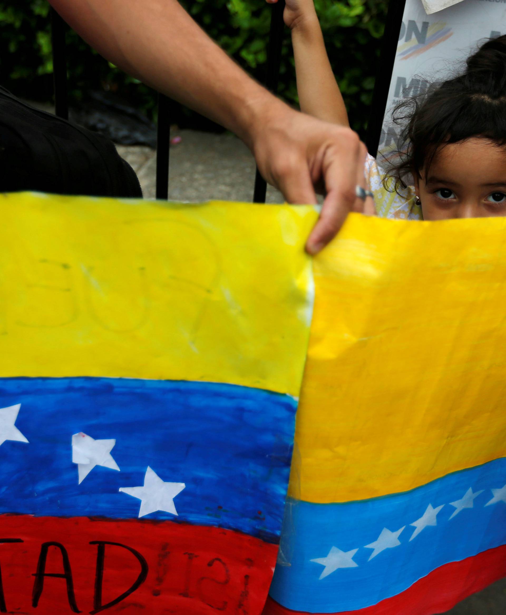 A girl looks over a poster painted with the flag of Venezuela, at the Simon Bolivar international bridge in Cucuta, Colombia