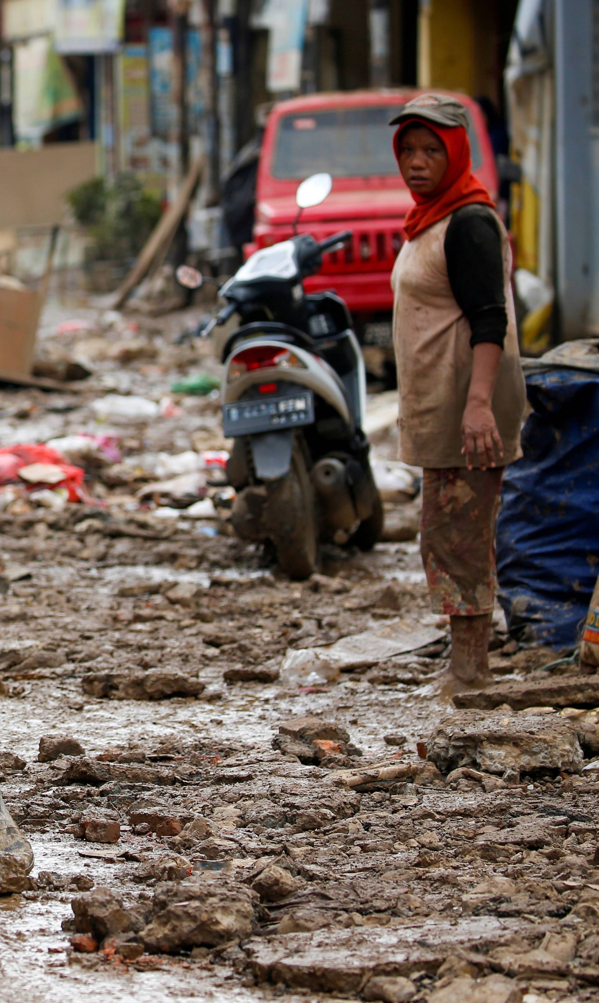 Man carrying a washing machine rides a motorbike as he collects items at a residential area affected by floods in Bekasi