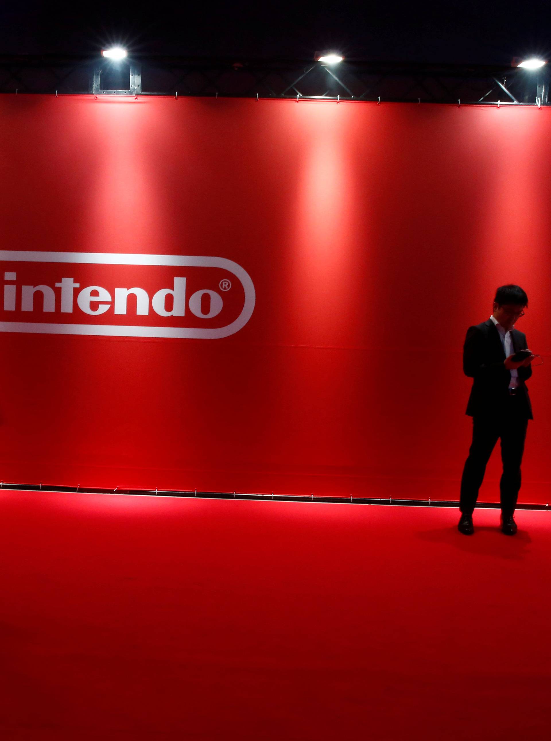 People stand in front of Nintendo's logo at the presentation ceremony of its new game console Switch in Tokyo
