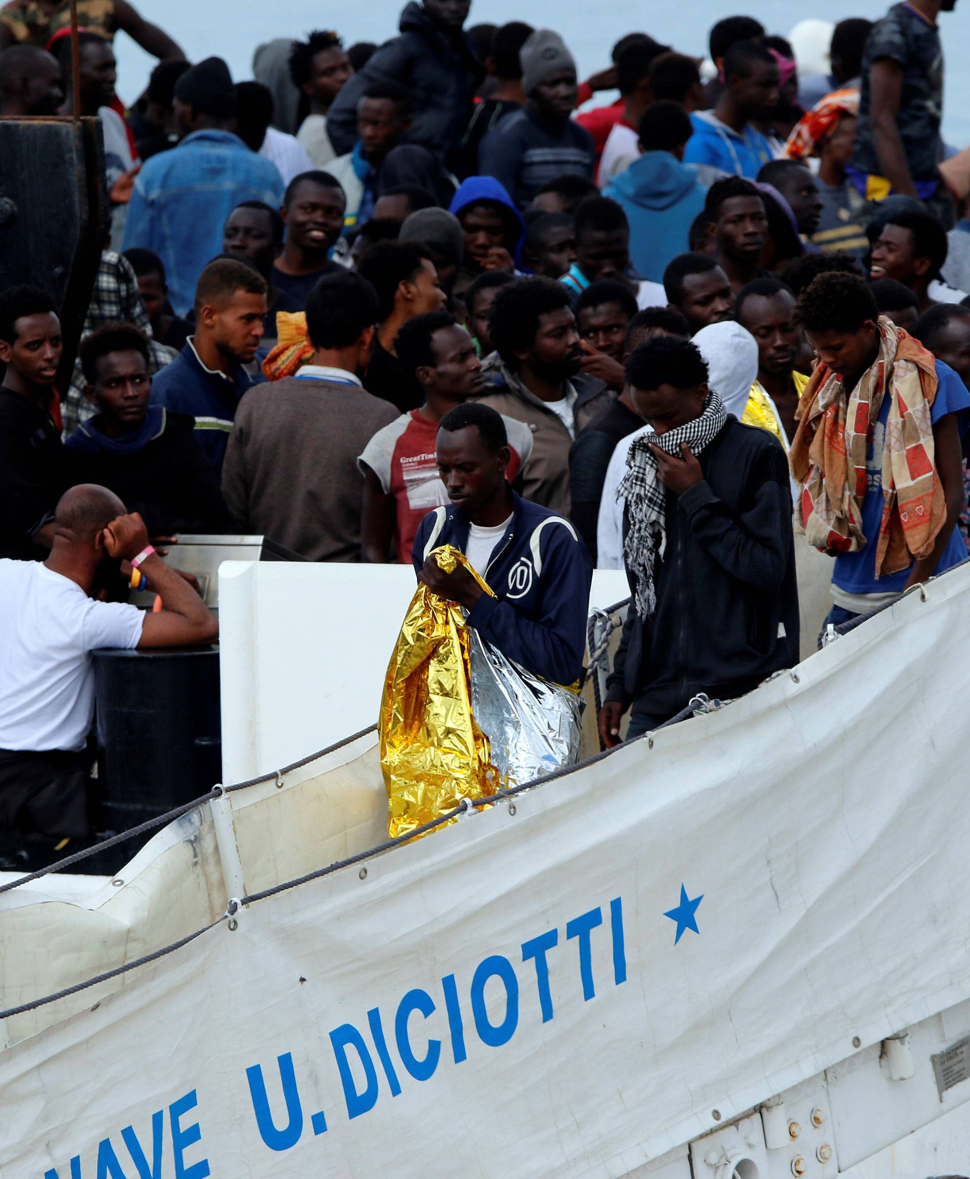 Migrants disembark Italian coast guard vessel "Diciotti" as they arrive at the port of Catania