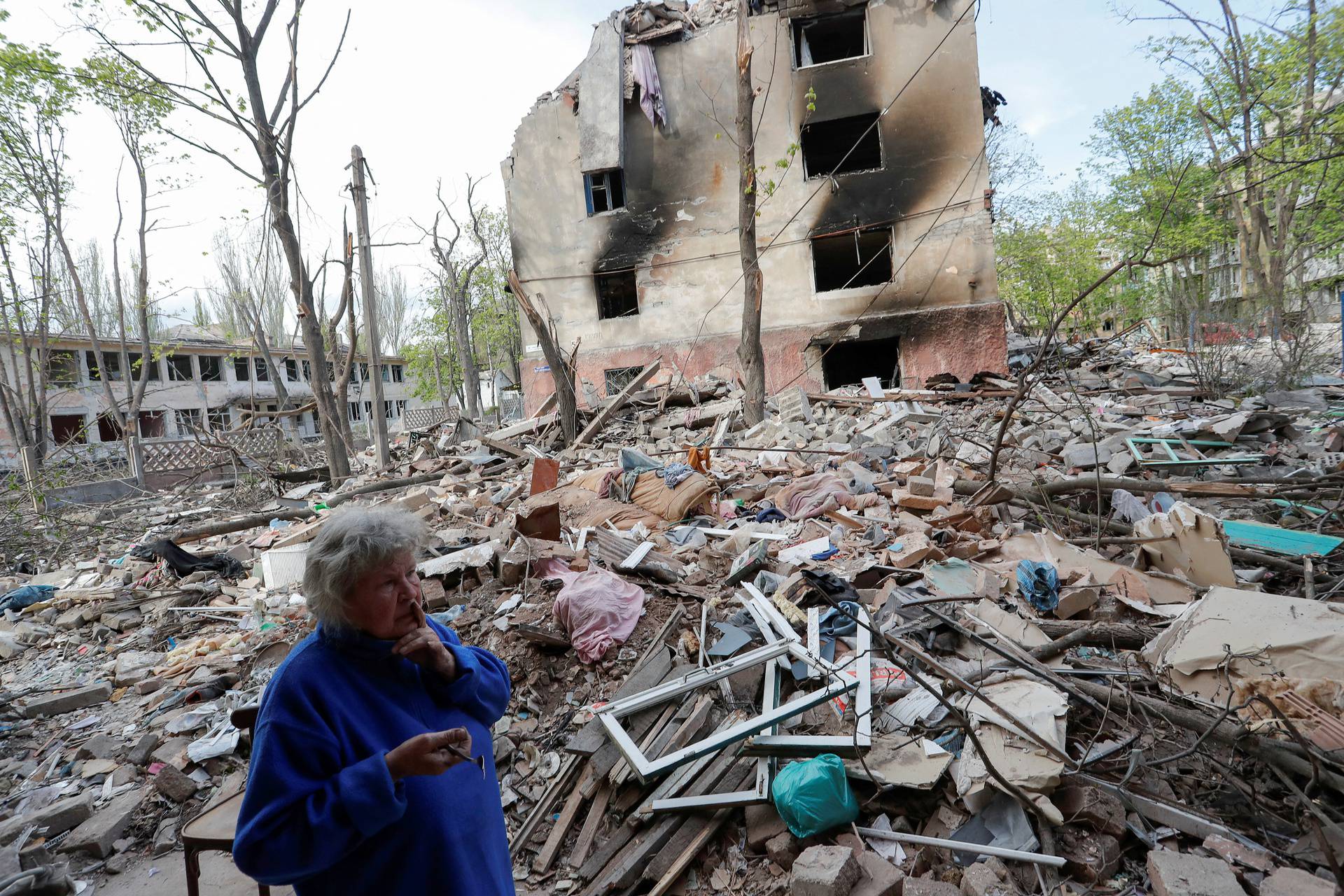 A local resident stands in a courtyard near a damaged building in Mariupol